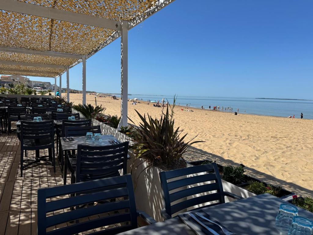 a restaurant with tables and chairs on the beach at Acadie Saint Victor - Hôtel restaurant -Face mer- Châtelaillon plage in Châtelaillon-Plage