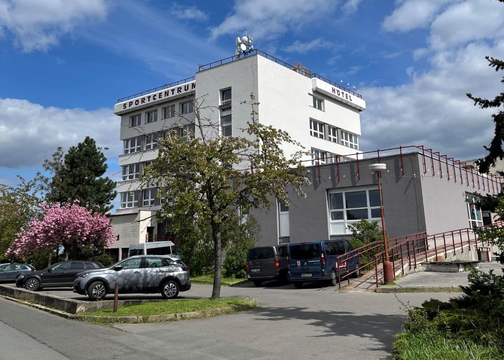 un edificio bianco con auto parcheggiate in un parcheggio di Sportcentrum Brandýs a Brandýs nad Labem-Stará Boleslav