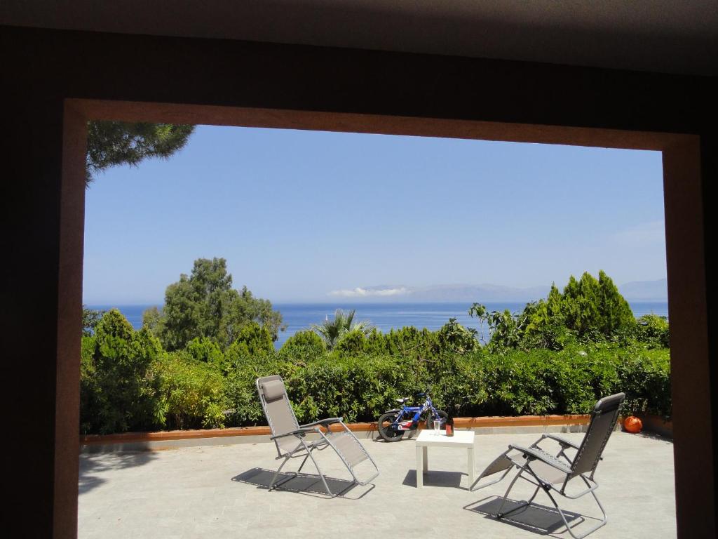 two chairs and a table on a patio with the ocean at Piccola Baia in Scopello