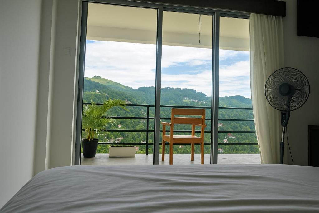 - une chambre avec un lit et une chaise en face d'une fenêtre dans l'établissement Glenview hotel & homestay, à Kandy