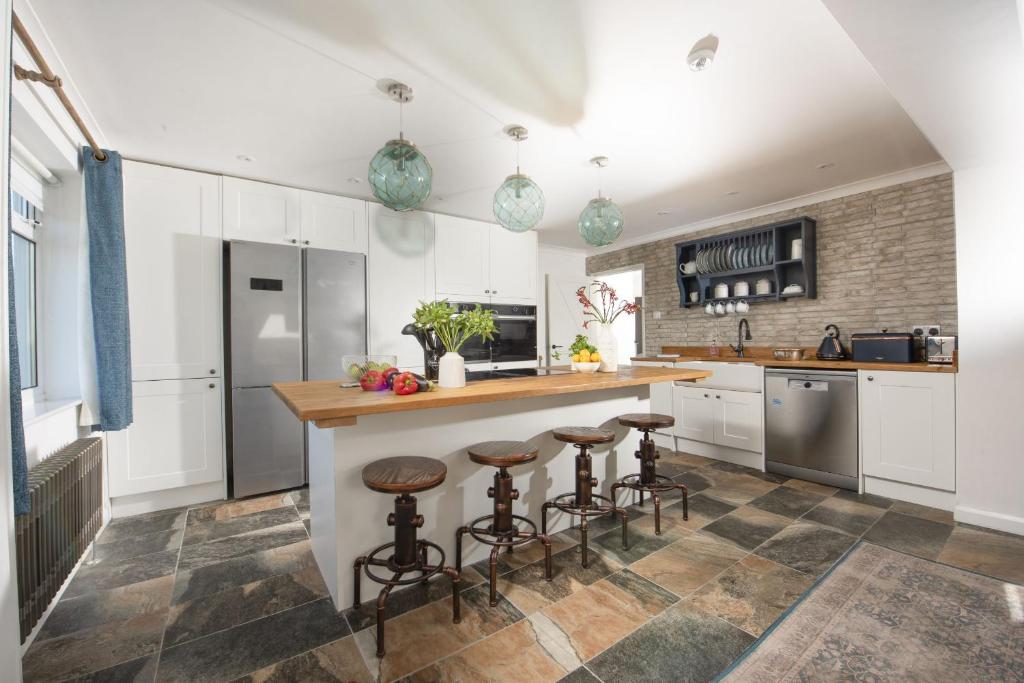 eine Küche mit weißen Schränken und Barhockern in der Unterkunft Sennen Sands- Free Parking - Free WiFi - Self Check In - Close to Beach - Pets Welcome in Sennen