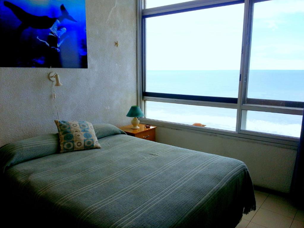 Un dormitorio con una cama y dos grandes ventanales. en Playa Club Apart, en Miramar
