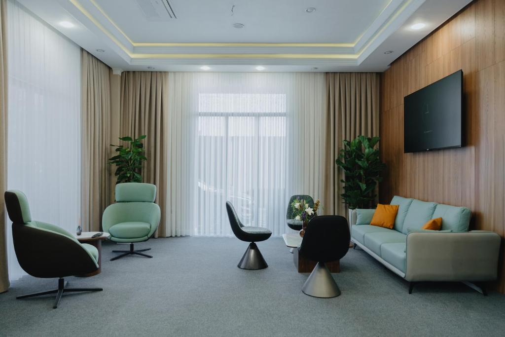 a living room with a couch and chairs and a tv at Bon Hotel Bishkek in Bishkek