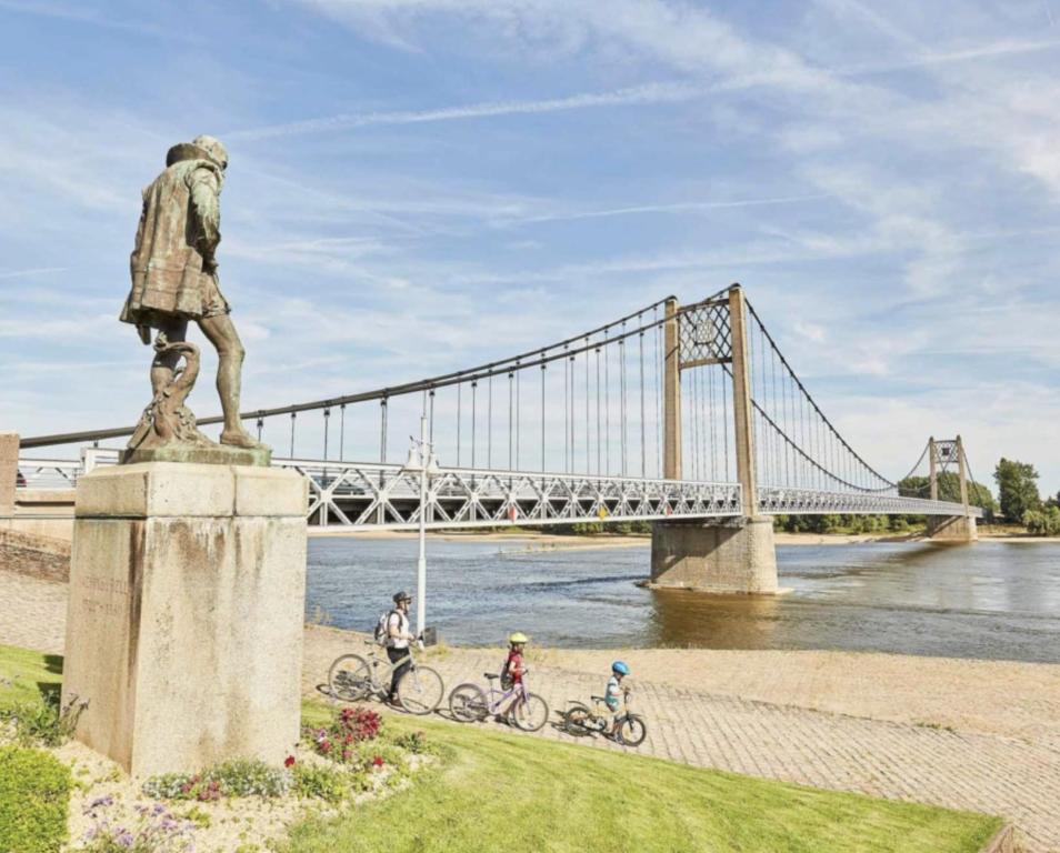 a statue of a man with two bikes in front of a bridge at Le Chai des Poilanes in Liré