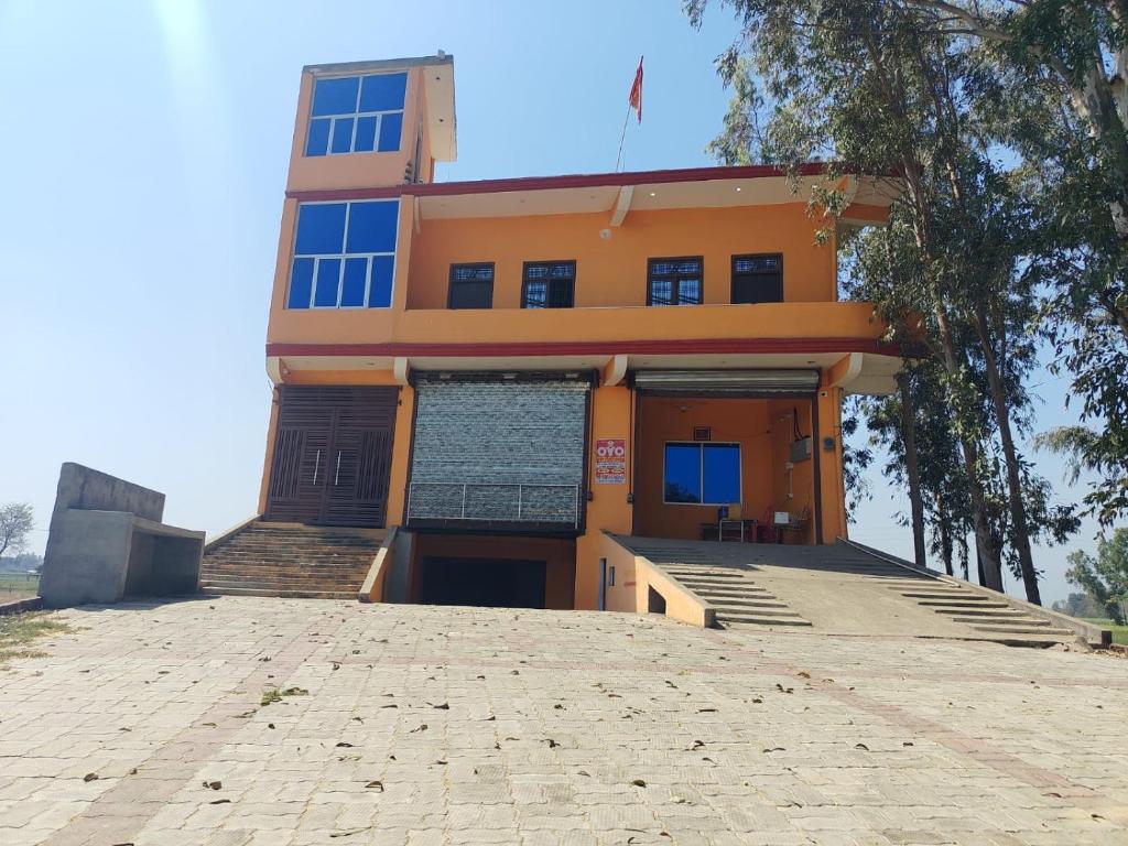 a large orange building with a stone driveway in front of it at Hotel diomand in Hardoī