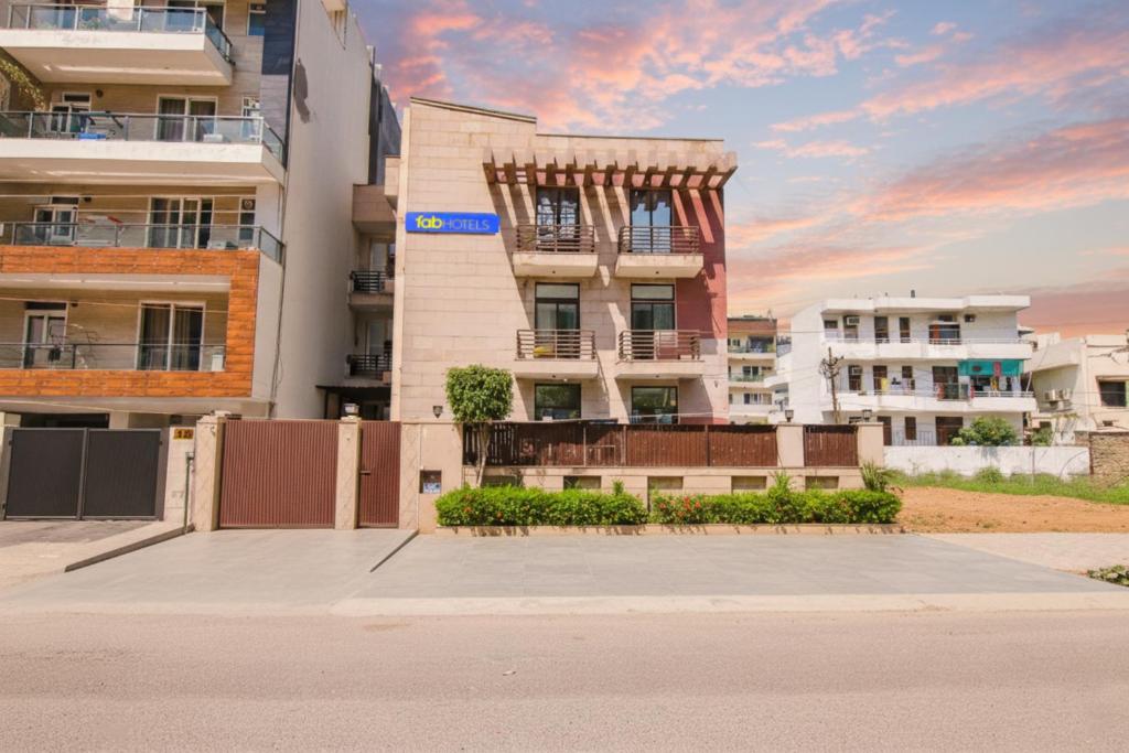 a tall apartment building with a sunset in the background at FabHotel JDM Residency in Gurgaon
