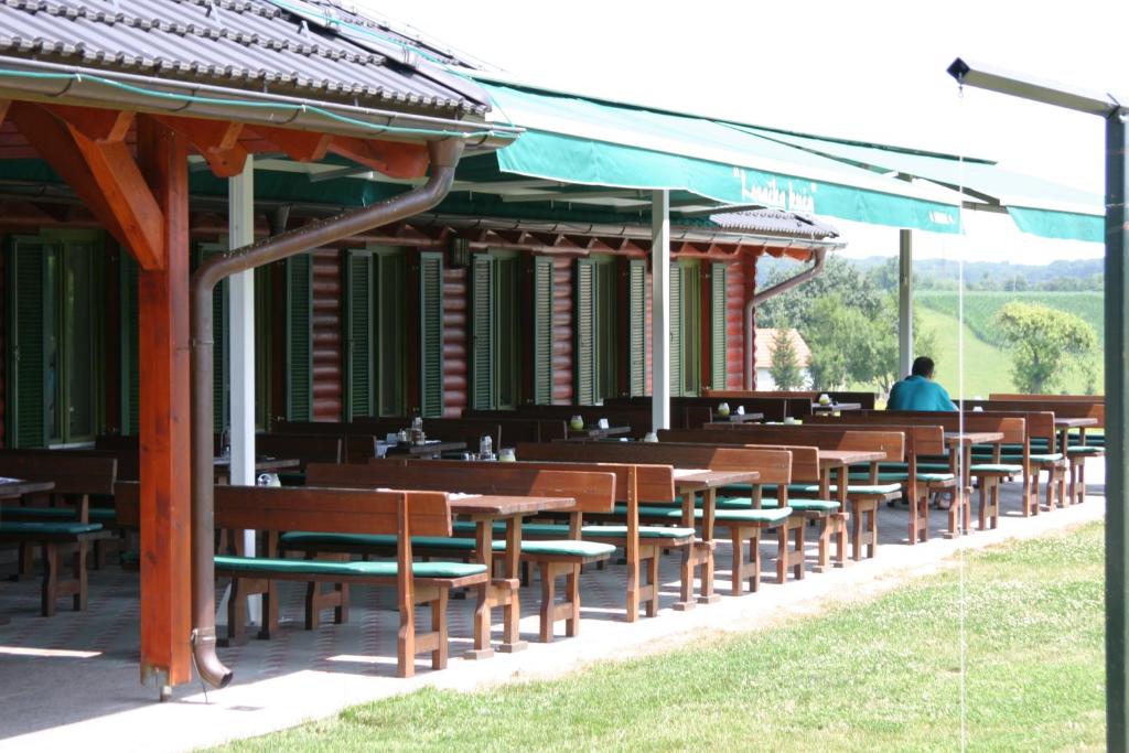 una fila de mesas y sillas de madera en un restaurante en Guest accomodation Lovacka kuca, en Grdak