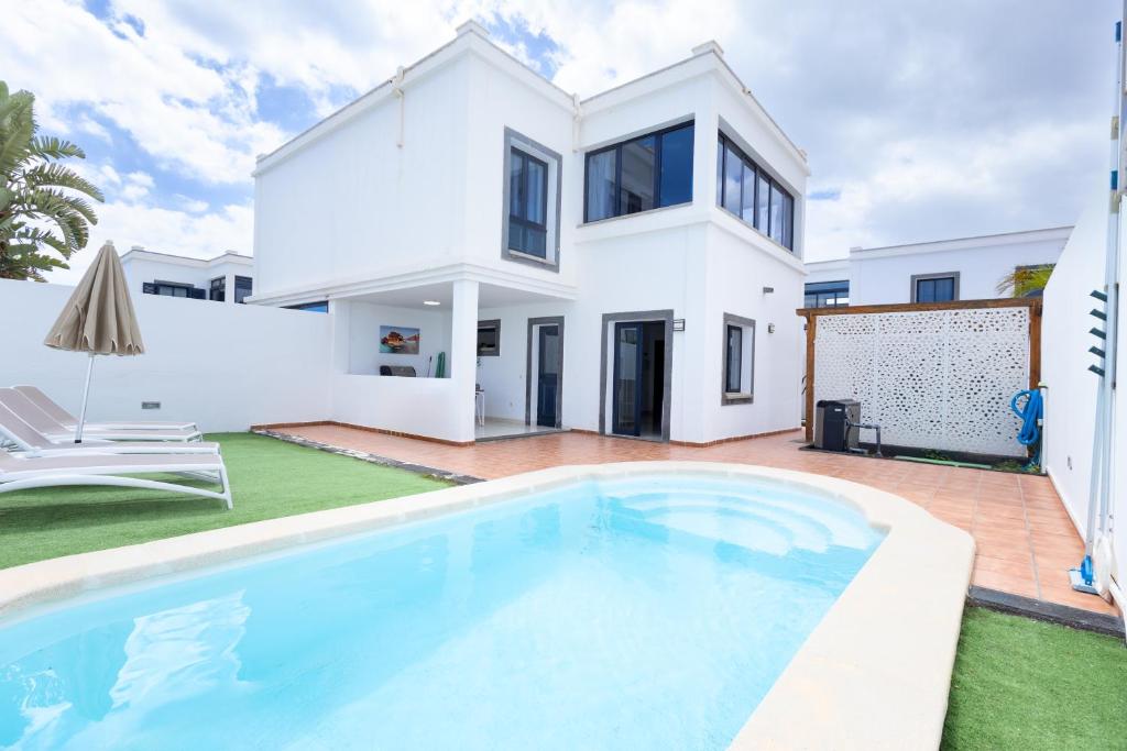 een wit huis met een zwembad ervoor bij Villa Piva in Playa Blanca