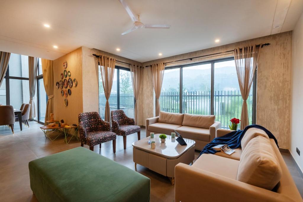 a living room with a couch and a table at SaffronStays Pebble House - 3BR riverside villa with glass walls, terraces & Nun River views, Dehradun in Dehradun