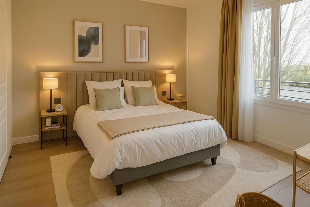 Un dormitorio con una cama grande con dos mesas y dos lámparas. en Zenao Appart'hôtels Saint-Mandé, en Saint-Mandé