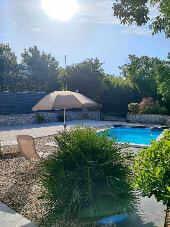 an umbrella and a chair next to a swimming pool at Villa Solterra in Grižane