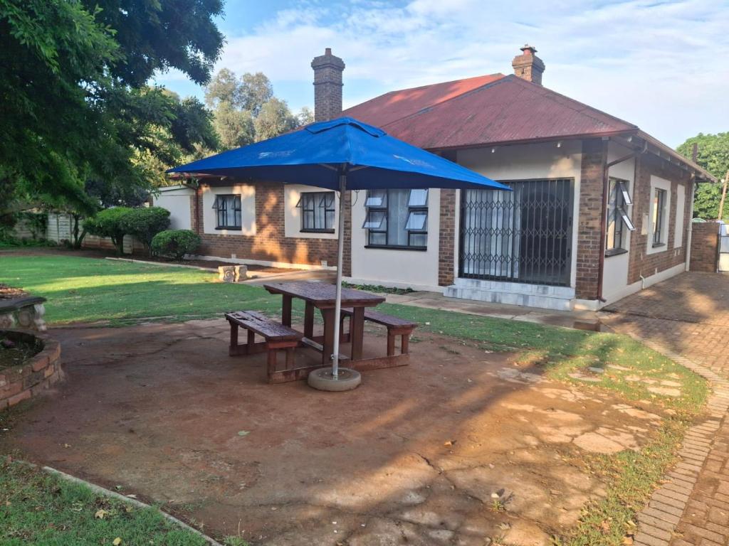 una mesa de picnic con una sombrilla azul delante de una casa en Good Morning Retreat, en Springs