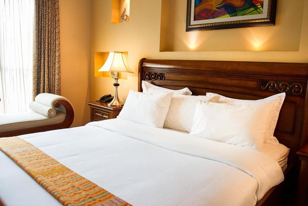 a bedroom with a large bed with white sheets and pillows at YOD Abyssinia International Hotel and Cultural Restaurant in Addis Ababa