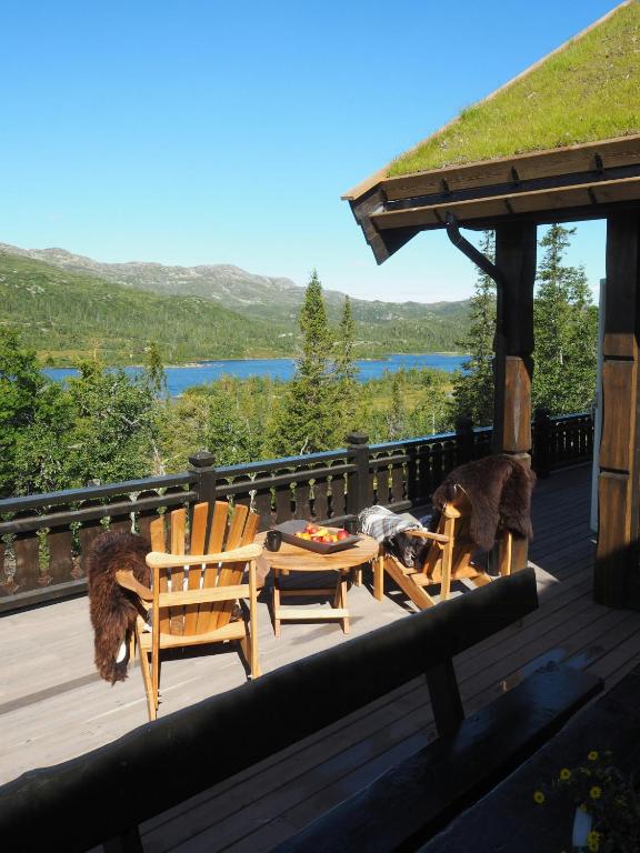 a deck with two wooden chairs and a table at Modern Mountain Cabin With A View Over The Sea in Vevle
