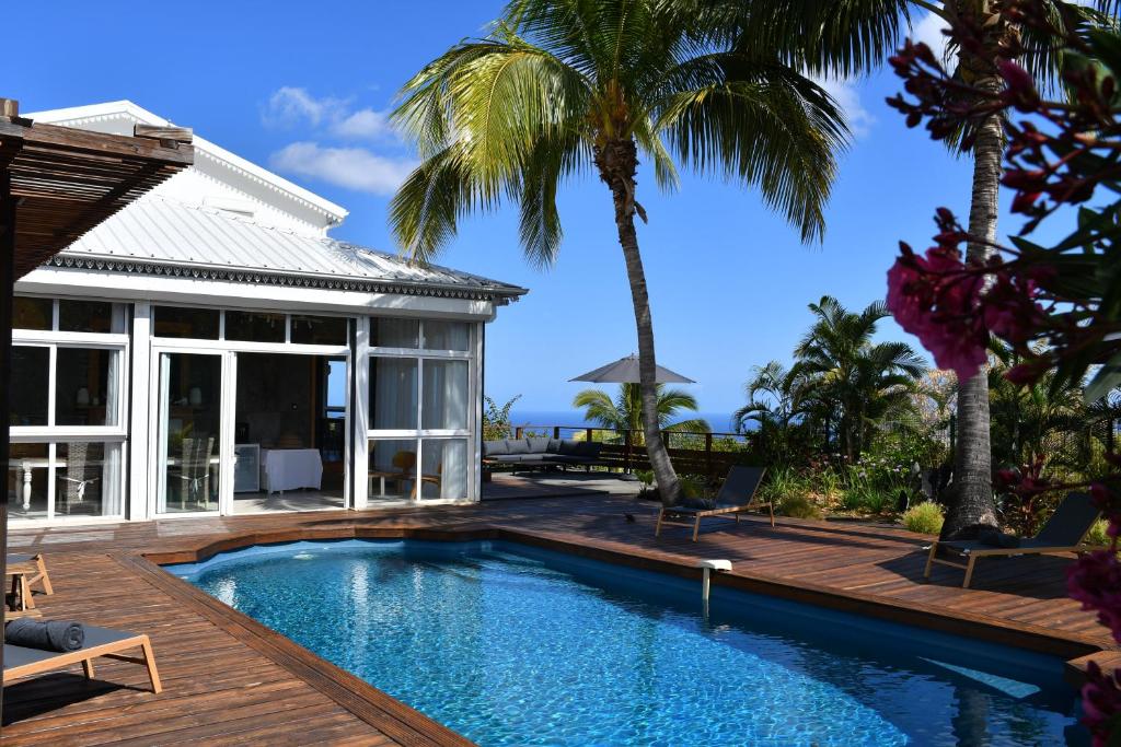 una piscina davanti a una casa con palme di Villa Kokoro a Saint-Paul