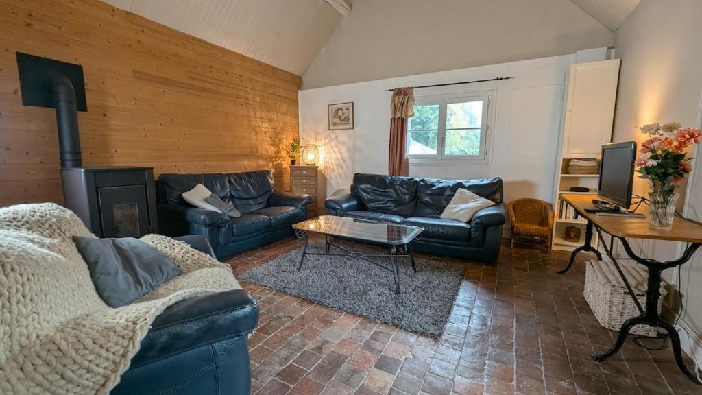 un salon avec deux canapés et une cheminée dans l'établissement La Tometterie - longère normande traditionnelle, à Chanteloup