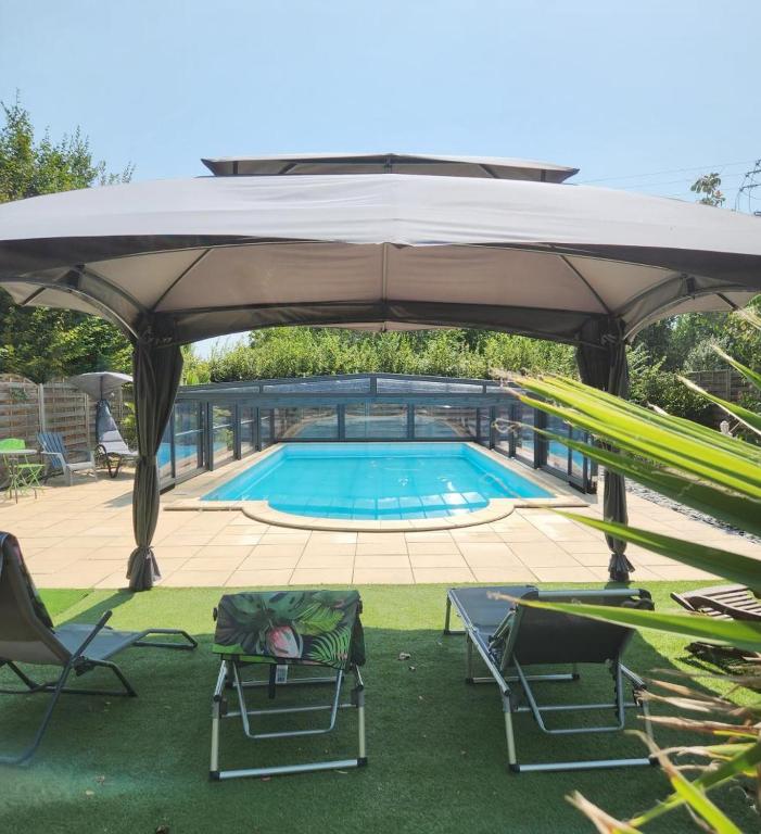 a swimming pool with chairs and a large umbrella at Le prieuré in Raslay