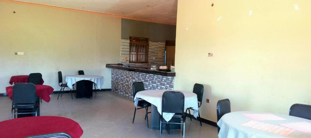 a dining room with tables and chairs and a fireplace at Lexus Motel Rwamwanja in Kamwenge