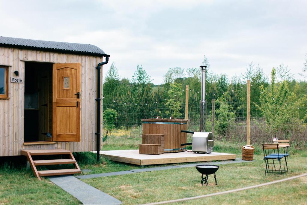 a small wooden shed with a television and a table at Shepherd's Huts in Barley Meadow at Spring Hill Farm in Oxford