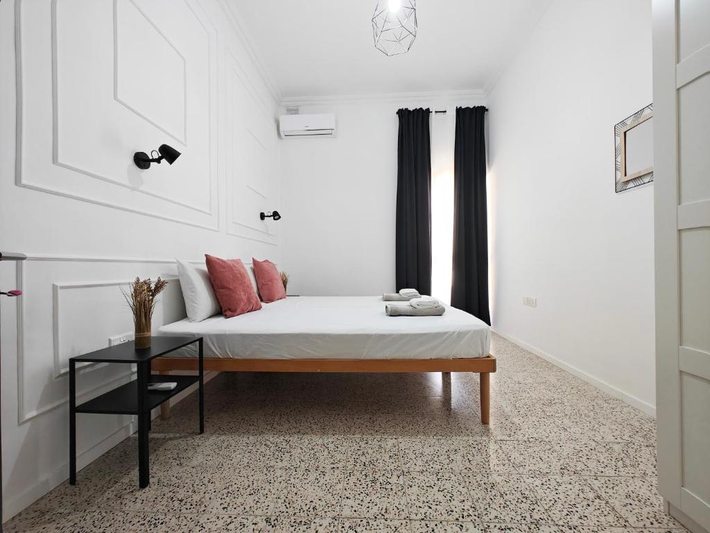 a white room with a bed and a table at Cosy room 6 in Tal-Pietà