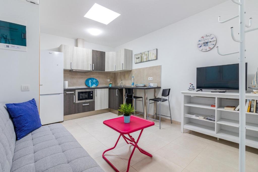 sala de estar con mesa roja y cocina en Arinaga Playa 4, en Agüimes