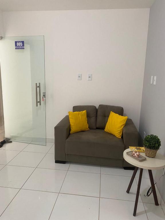 a couch with two yellow pillows in a living room at Apartamento dois quartos acolhedor prox Hospital Regional e Rodoviária in Santo Antônio de Jesus