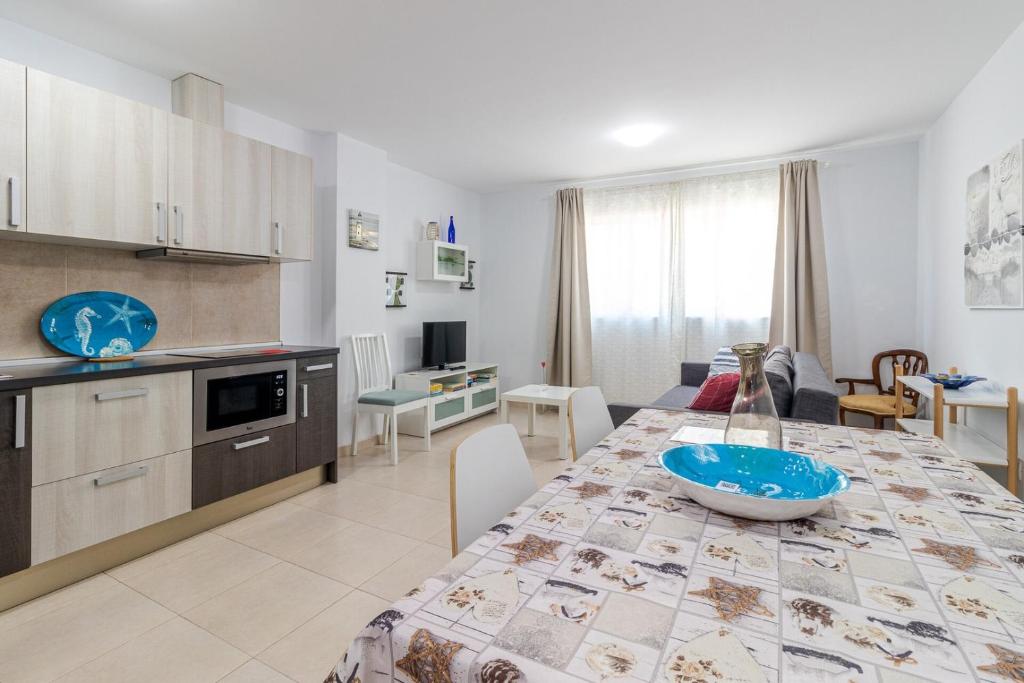 Una cocina y una sala de estar con una mesa con un cuenco encima. en Arinaga Playa 2, en Agüimes