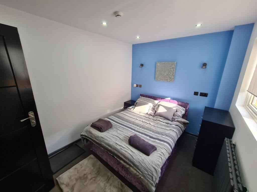 a bedroom with a bed with a blue wall at YPS Studio Rooms in Peterborough