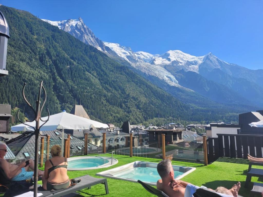 a group of people sitting in chairs by a pool with mountains at Park Hotel Suisse & Spa in Chamonix-Mont-Blanc