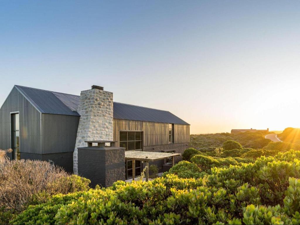 a house in the middle of a field with bushes at Black Barn At Romansbaai in Goudiniweg