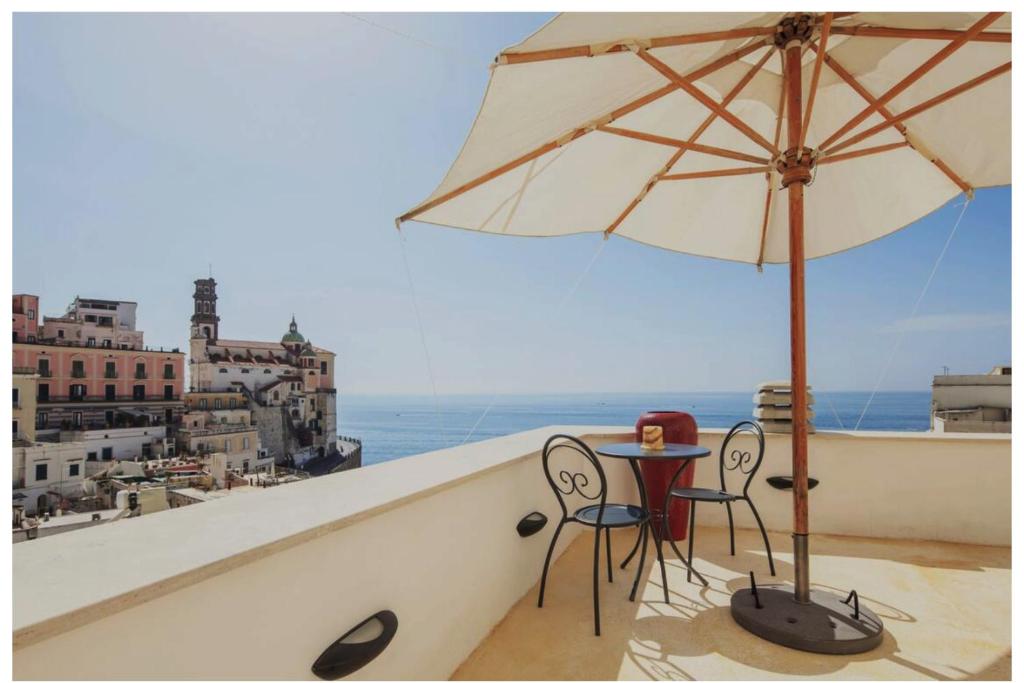 a table and chairs on a balcony with an umbrella at Amalfi 2 rooms 1fl no terrace 2fl private terrace sea view in Atrani
