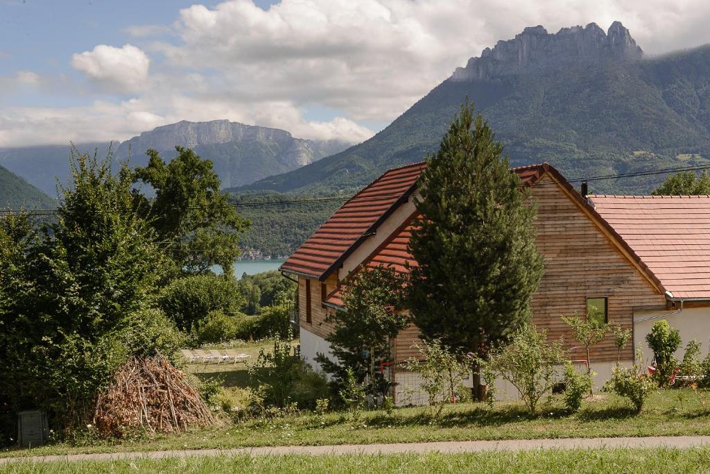 una casa de madera con montañas en el fondo en Villa Panoramiqua - Vue 180 sur le Lac d'Annecy et les montagnes, en Saint-Jorioz