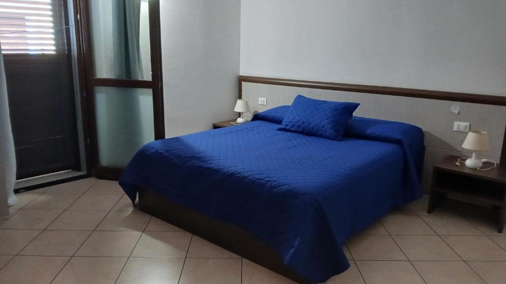 a bedroom with a bed with blue sheets and a window at Domo - Guest-House Il Nespolo Fiorito in Orosei