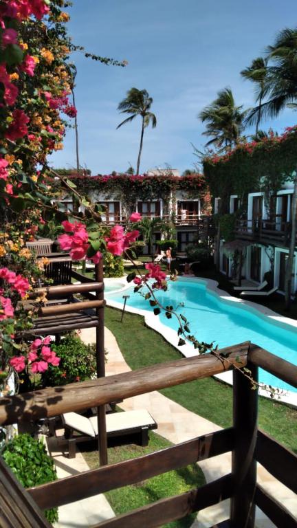a fence next to a swimming pool with pink flowers at Wind e Blue in Jericoacoara