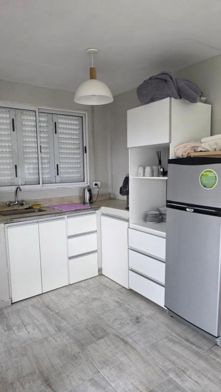 eine Küche mit weißen Schränken und einem schwarzen Kühlschrank in der Unterkunft Verano pleno in Monte Hermoso