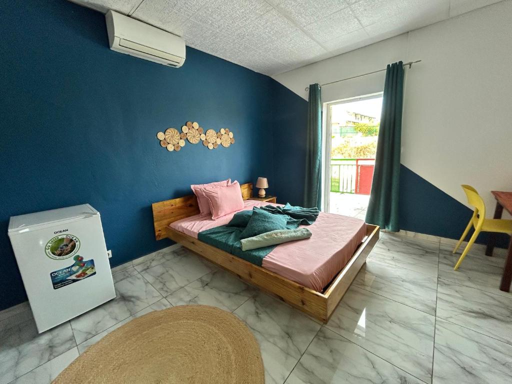 a bedroom with a bed and a blue wall at Steiladay hébergement 976 in Pamandzi