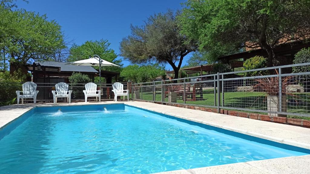 a swimming pool with chairs and a fence at Cabañas Lo de Alberto in Santa Rosa de Calamuchita
