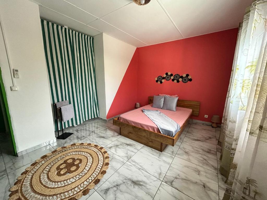 a bedroom with a red wall with a bed and a rug at SteilaDay Hébergement 976 in Pamandzi