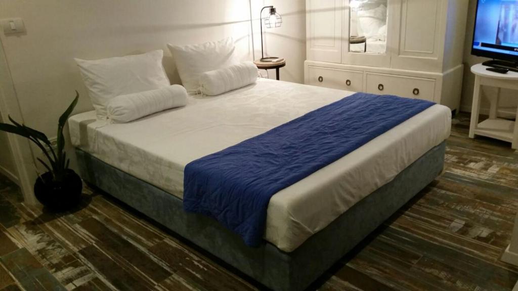 een slaapkamer met een bed met een blauwe deken en een televisie bij Tel Aviv Roof Apartment in Tel Aviv
