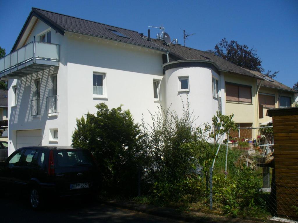 una casa blanca con un coche aparcado delante de ella en Ferienwohnung Rheinaue, en Colonia