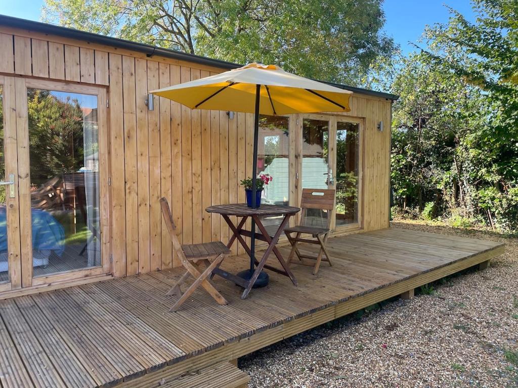 a wooden deck with a table and an umbrella at The Cabin at Box Cottage in Somerton