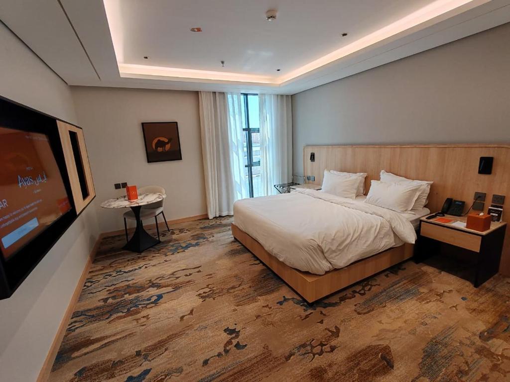 a bedroom with a large bed and a flat screen tv at Ayas Hotel in Hail