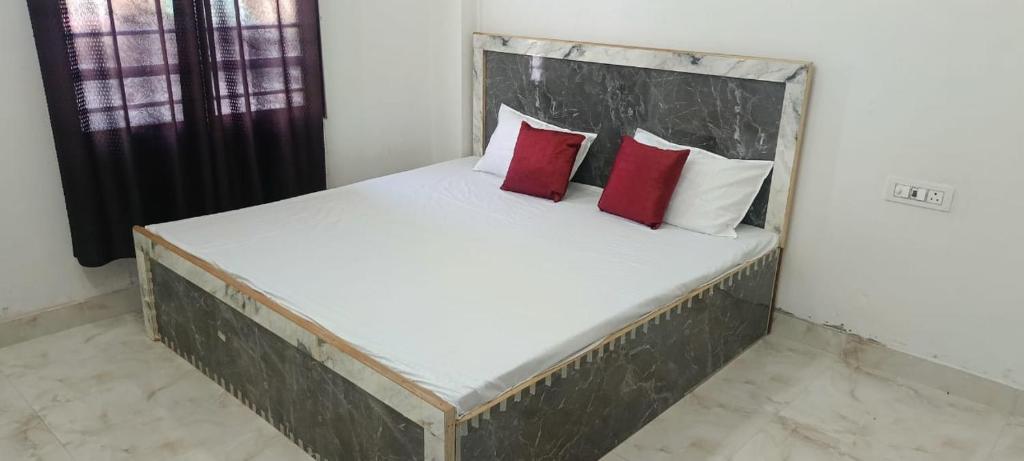 a bed with two red pillows in a room at Radha Rani Dham in Rādha Kund