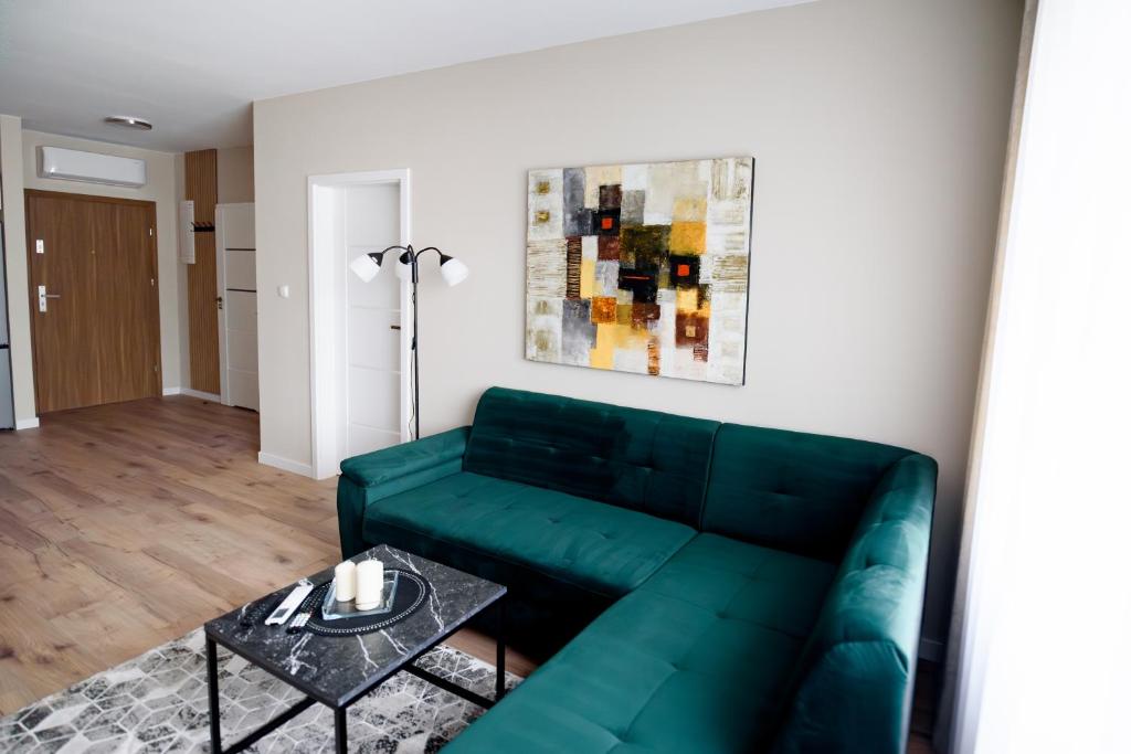 a living room with a green couch and a table at Apartamenty EUROPA in Jasło