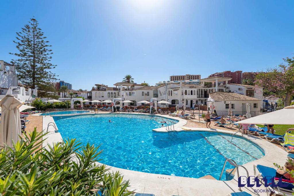 een zwembad in een resort met blauw water en witte gebouwen bij 2 BR Beach and Pool By Better Bookings in Arroyo de la Miel