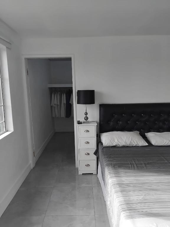 a bedroom with a bed and a dresser with a lamp at Clarke Place in Mandeville