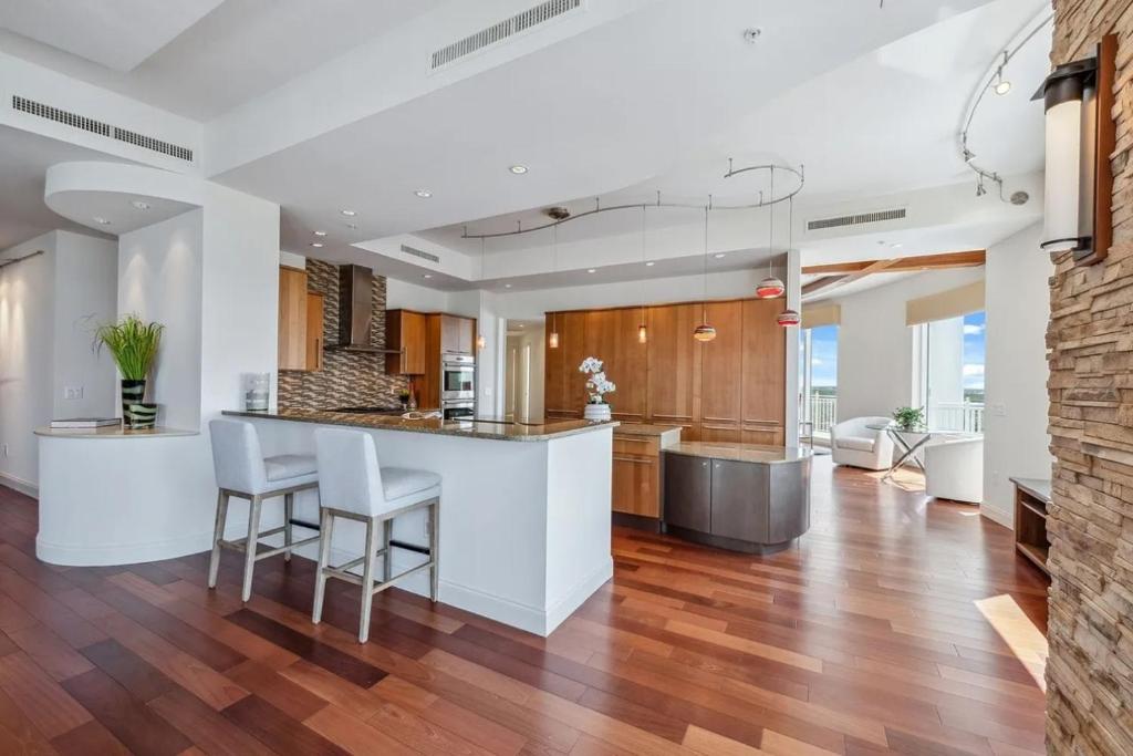 a kitchen with wooden floors and a counter with stools at Penthouse In The Sky With Water Views in Naples