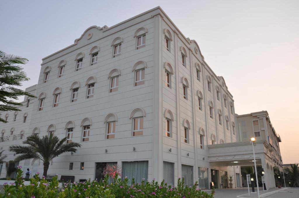 a large white building with a lot of windows at Royal Gardens Hotel in Sohar