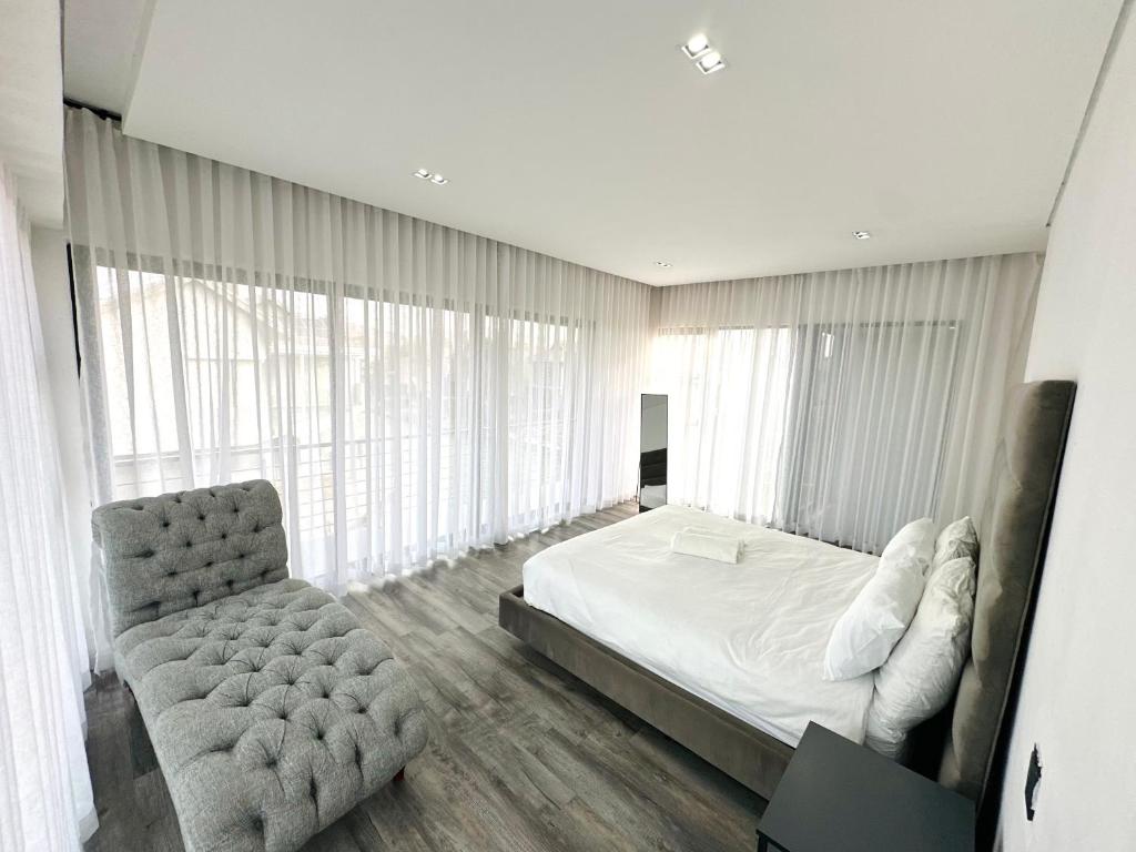 a bedroom with a bed and a chair and windows at Sucassa 54 - Luxury 2 Bedroom - Dam & Mountain View in Hartbeespoort