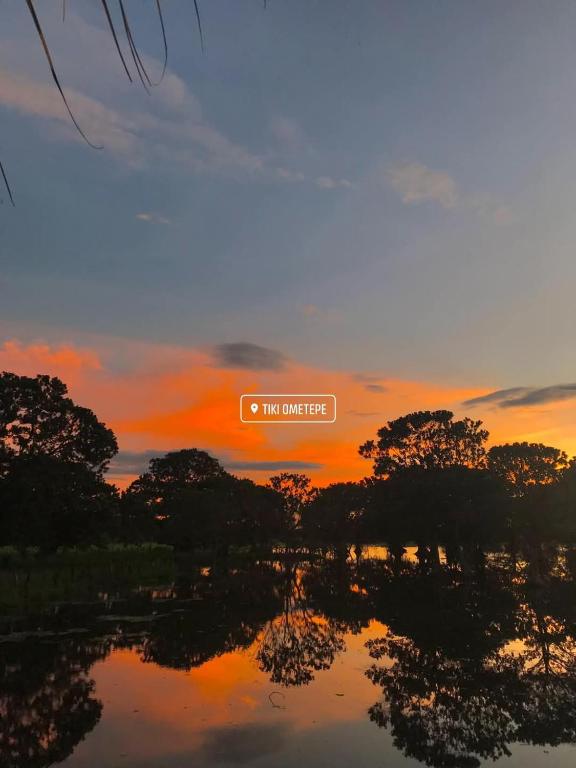 a sunset over a lake with a sign that reads ohmile bridge at TiKi Hostel Island Ometepe in Rivas